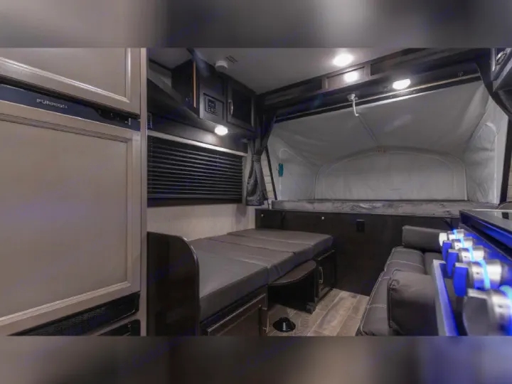 Compact RV rental interior featuring a convertible dinette bed, pop-out sleeping area, kitchen, and refrigerator.. Jayco Jay Feather 2021