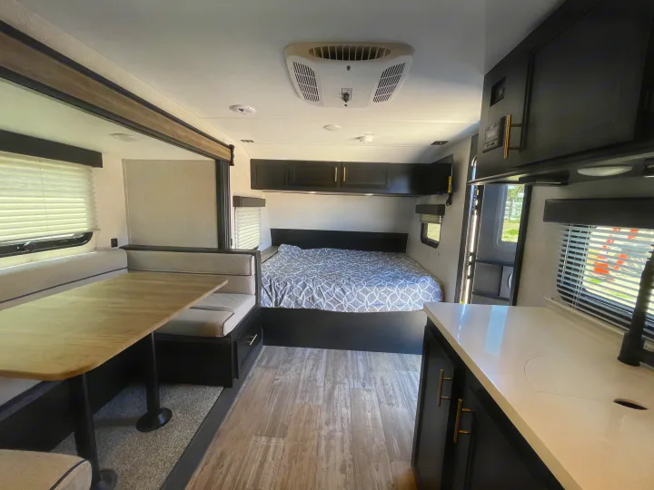 An RV rental's modern interior featuring a cozy bedroom, dinette, and kitchen area.. Forest River Cherokee Wolf Pup 2021