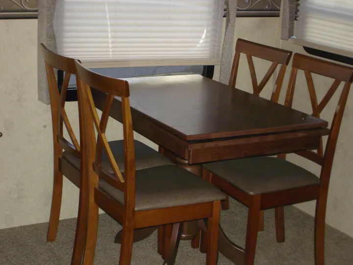 RV rental's compact dining area: a wooden table with four chairs and pleated window blinds. Enjoy meals comfortably.. Flagstaff 26FKWS Super Lite 2016