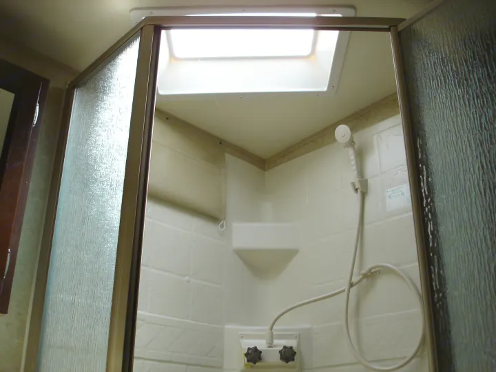 Interior of an RV rental shower, showing the textured glass door, skylight, showerhead, and water controls.. Flagstaff 26FKWS Super Lite 2016