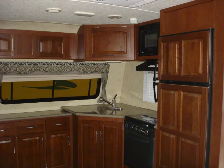 Explore the well-equipped kitchen of this RV rental, featuring warm wood cabinets, microwave, fridge, sink, and stove.. Flagstaff 26FKWS Super Lite 2016