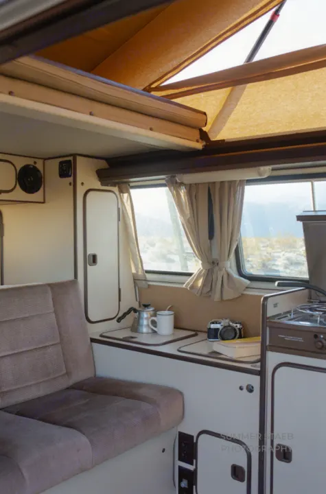Inside a classic pop-top RV rental: cozy seating, a compact kitchen with coffee, and desert views. Ideal for travel!. Volkswagen Westfalia 1986