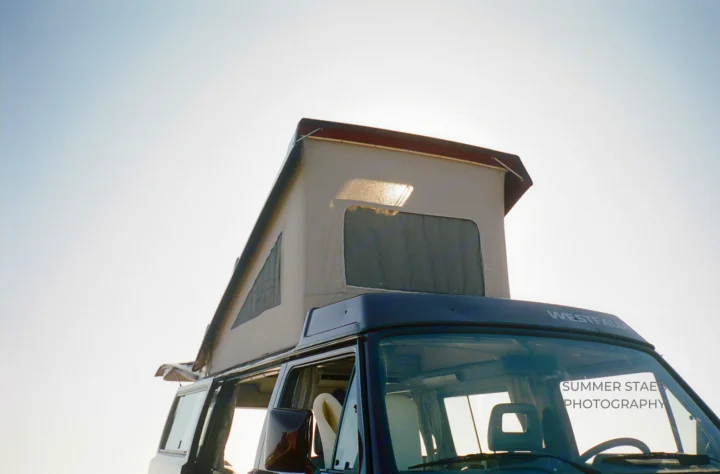A classic Westfalia pop-top camper van, with its roof extended against a bright sky, ready for your next RV rental adventure.. Volkswagen Westfalia 1991