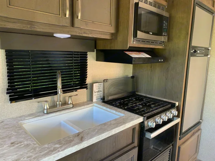 Double sink next to stovetop with oven underneath. Jayco Jay Flight 2021