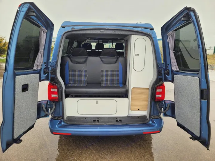 Spacious blue camper van rear with open doors, revealing a comfy bench seat and storage for your next RV rental adventure.. Volkswagen T5 2018