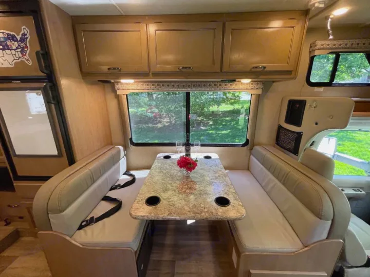 Spacious RV rental dinette setup with a table, comfortable benches, overhead storage, and large scenic windows.. Thor Motor Coach Four Winds 2019