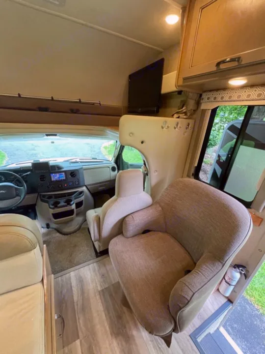 Inside an RV rental: swivel front seats, TV, and overhead storage, showing the practical living and cab area.. Thor Motor Coach Four Winds 2019