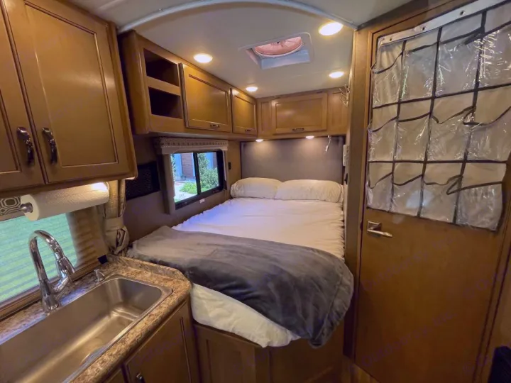 Comfortable RV rental interior with bed, kitchen sink, and ample storage for your mobile adventures.. Thor Motor Coach Four Winds 2019