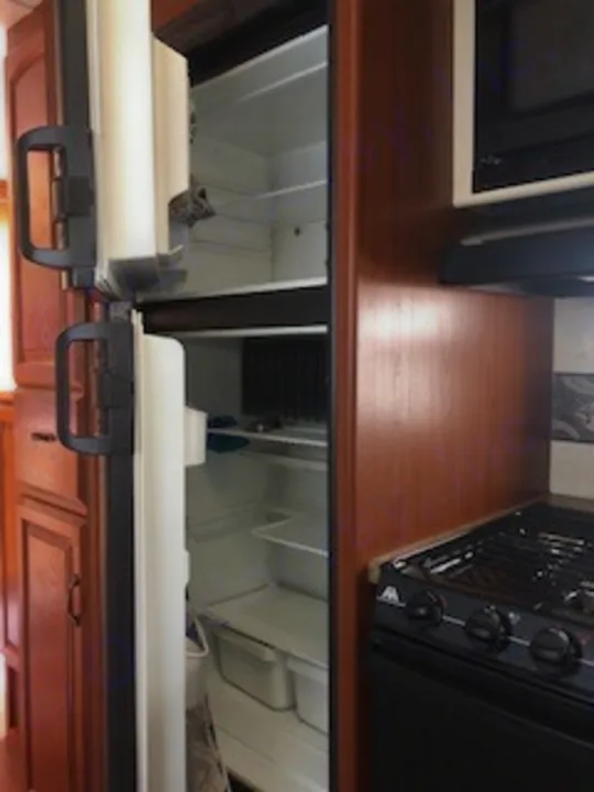 RV rental kitchen interior with open refrigerators, a microwave, and stove, ideal for convenient camping trips.. Keystone RV Outback 2011