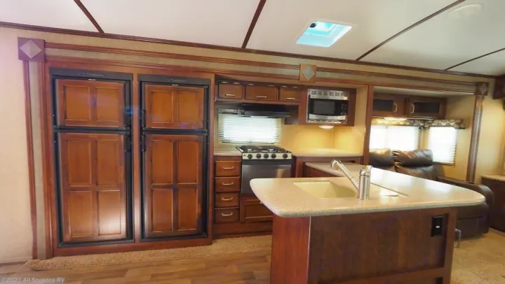 RV rental interior showcasing a spacious kitchen with island sink, dual refrigerators, microwave, stove, and comfortable recliners.. Keystone Outback 2016