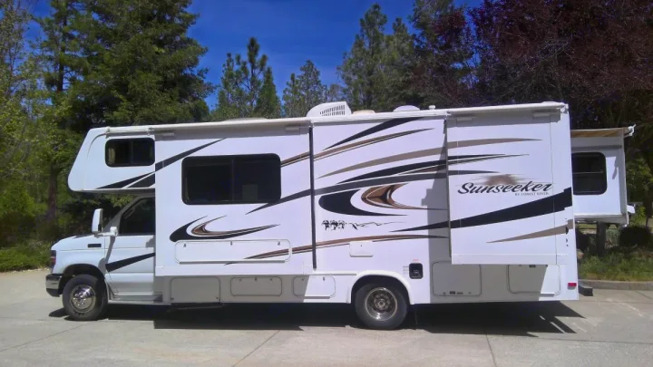 A white Sunseeker RV or motorhome is shown from the side with its slide-outs extended, ready for an rv rental trip.. Forest River Sunseeker LE 2014