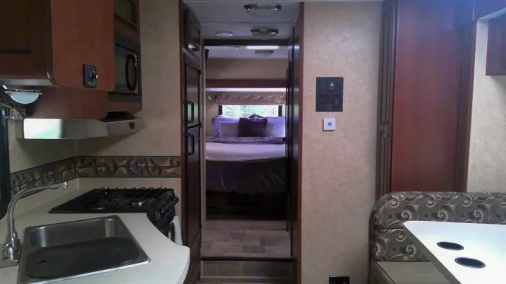 RV rental interior featuring a full kitchen with stove and sink, a cozy bedroom, and a comfortable dinette area.. Forest River Sunseeker LE 2014