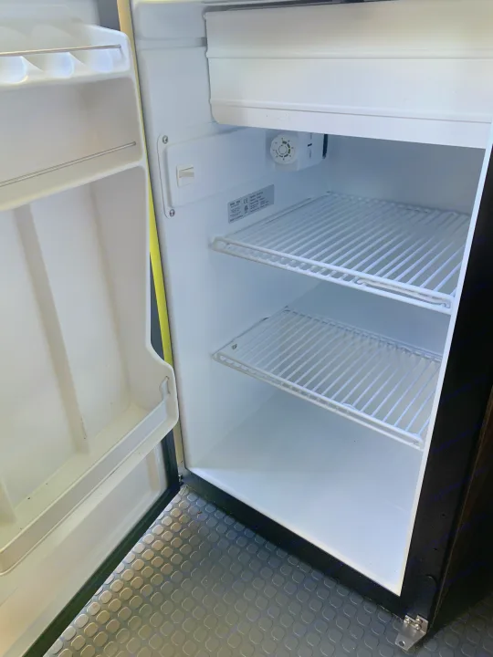 Empty and clean interior of an RV rental refrigerator, showing its wire shelves and door storage.. Winnebago Winnebago 2021