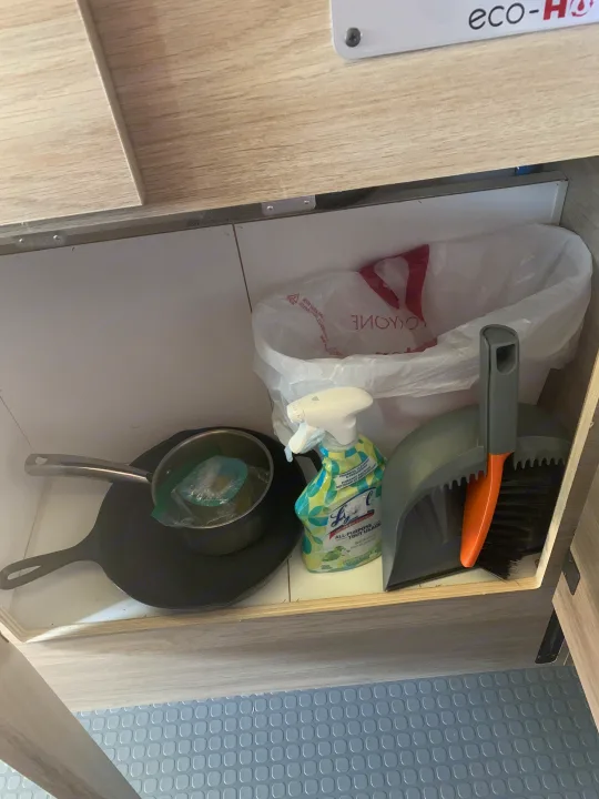 RV rental under-counter storage: Lys Lysol cleaner, dustpan/brush, skillet, and trash bag for compact living.. Winnebago Winnebago 2021