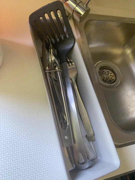 RV rental kitchen: a white utensil caddy holds a black spatula, tongs, and forks next to a stainless steel sink.. Winnebago Winnebago 2021