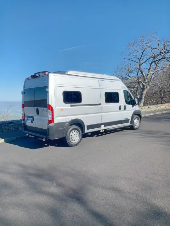 A silver Winnebago Solis RV rental is parked with a scenic valley view on a clear day, ideal for adventure.. Winnebago Winnebago 2021