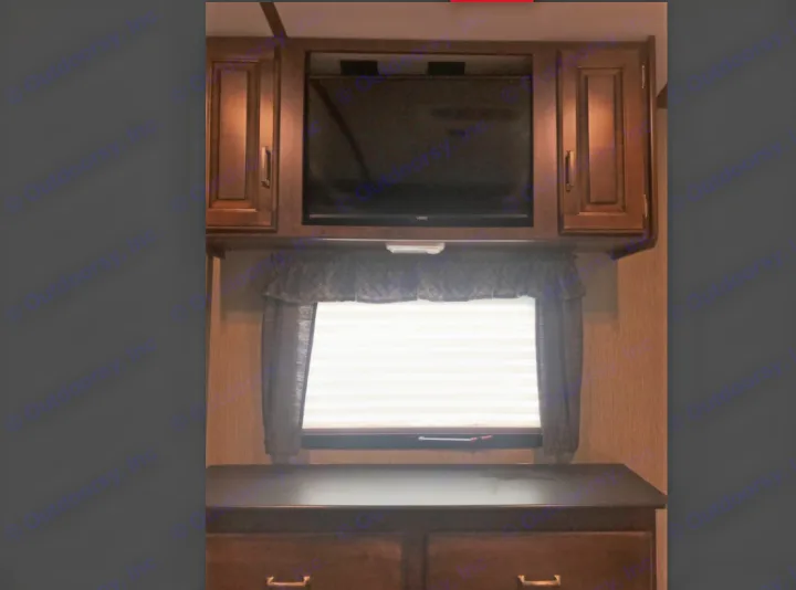 View inside an RV rental showing a TV, window with blinds, and lower dresser unit.. Keystone Outback 2018