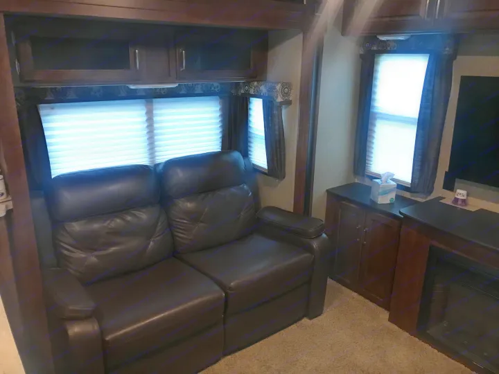 Cozy RV rental living area with brown leather recliners, multiple windows, and a built-in TV/fireplace.. Keystone Outback 2018