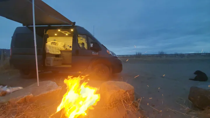 Cozy night camping! This RV rental offers a warm campfire, van life comfort, and a furry friend under a vast sky.. Ram Promaster 2020