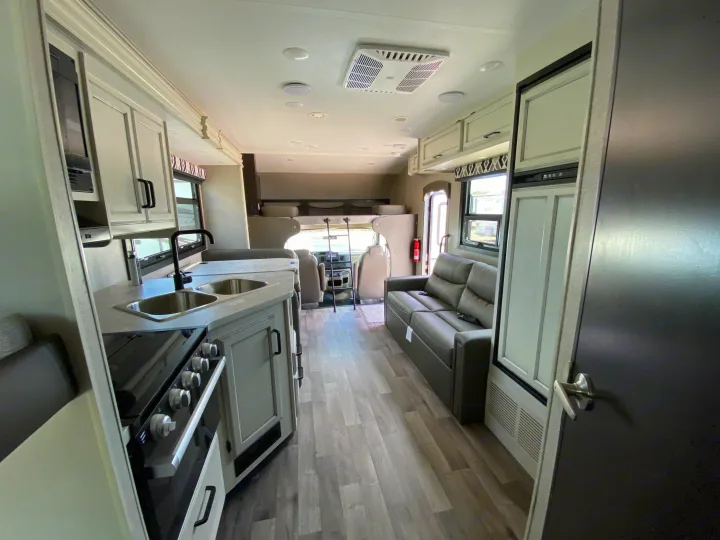 Spacious rv rental interior featuring a full kitchen, comfortable sofa, and cab-over bunk, perfect for family adventures.. Jayco Redhawk 2025