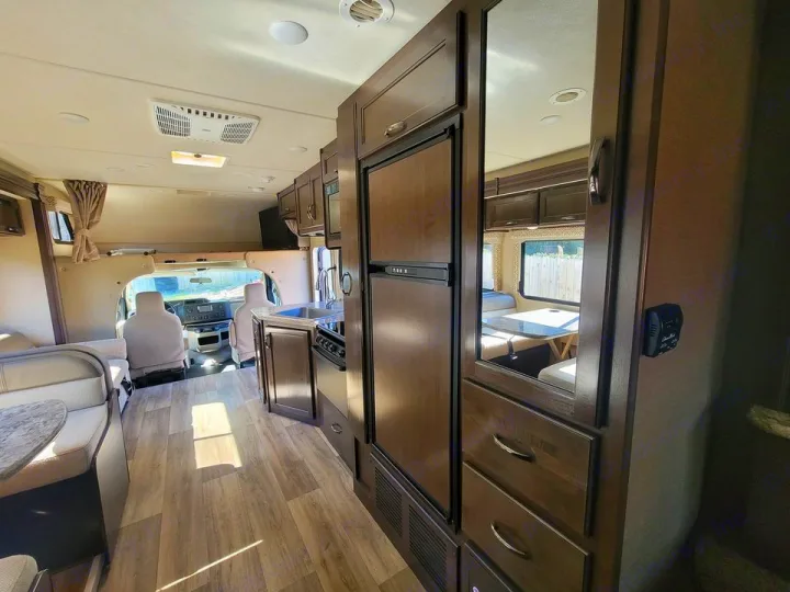 Inside a modern RV rental: a bright, clean interior with a full kitchen, dinette, and front cockpit.. Thor Motor Coach Freedom Elite 2019