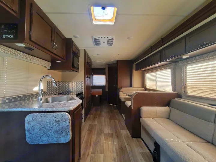 Bright RV rental interior with a functional kitchen, cozy dinette, and lounge area. Ideal for travel comfort.. Thor Motor Coach Freedom Elite 2019