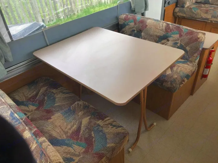 Cozy RV rental dinette featuring a square table, colorful patterned bench seats, and a fire extinguisher.. Coleman Other 2000