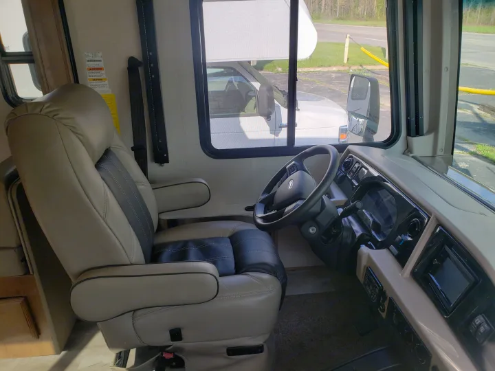 RV rental interior: driver's seat, steering wheel, dashboard, and a clear view out the front window.. Holiday Rambler Admiral 2021
