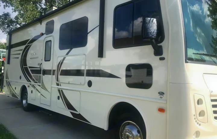 Bright white RV rental, a motorhome with bold black & gray graphics, parked on a driveway, ready for adventure.. Holiday Rambler Admiral 2021
