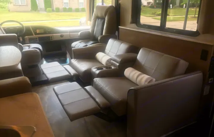 Step into an RV rental featuring a driving cockpit and cozy living area with recliners and extended footrests.. Holiday Rambler Admiral 2021