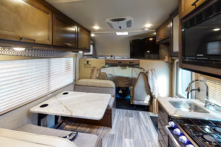 Spacious RV rental interior featuring a dinette, kitchen, and overhead bunk bed, ideal for adventure.. Thor Freedom Elite 2021