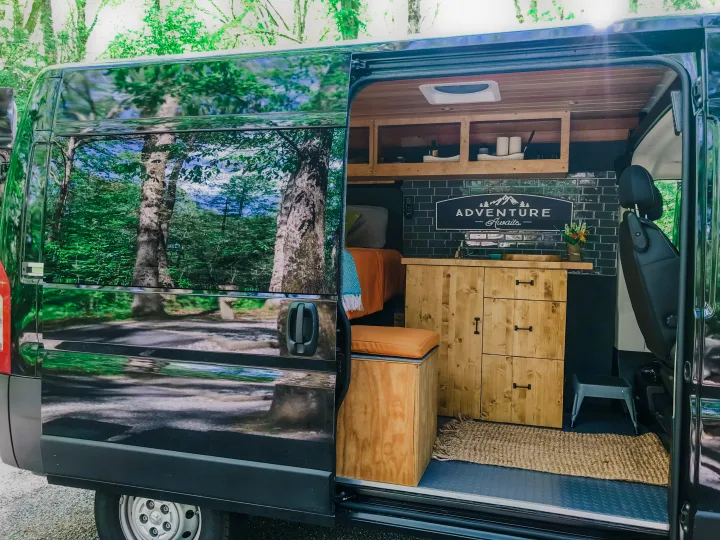 Step inside this custom rv rental camper van with a cozy bed, kitchenette, and wooden accents, ready for adventure.. Ram Promaster 1500 2021