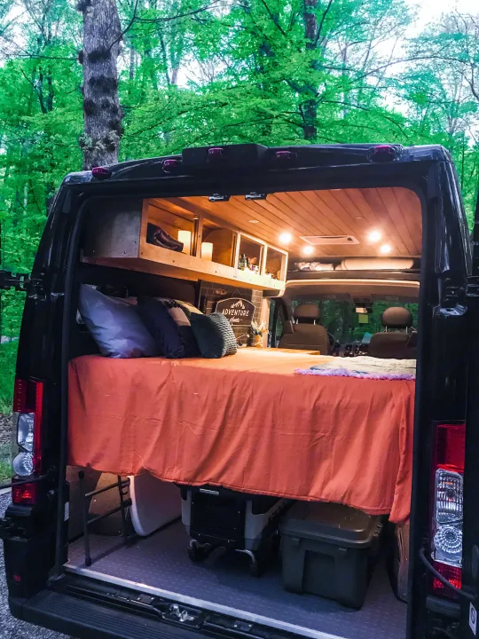 Open rear of a cozy camper van interior with bed, storage & lights. Perfect for an RV rental adventure in nature.. Ram Promaster 1500 2021