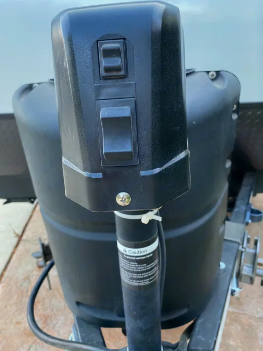 RV rental: Detail of the power tongue jack, with control switches, and black propane tank cover on the trailer hitch.. Forest River Surveyor 2021
