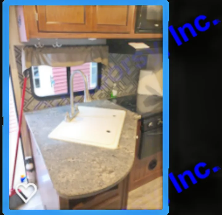 Inside your RV rental: a well-equipped kitchen with a sink, cutting board, microwave, and stove. Functional camper interior for trips.. Heartland M29 2017