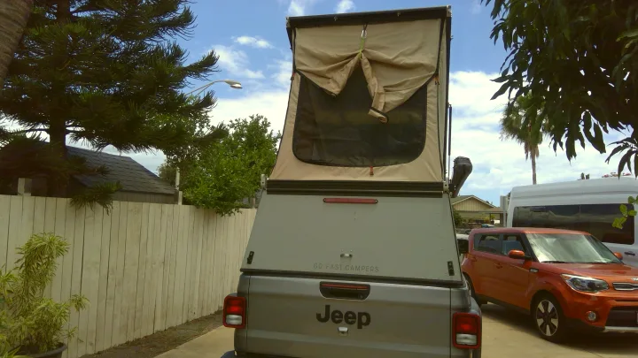 This grey Jeep Gladiator pickup with a tan pop-up camper, an excellent RV rental option for outdoor adventures and overlanding.. Jeep Gladiator 2020