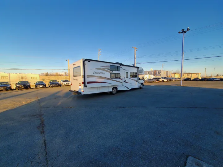 Sunseeker RV parked in a sunny dealership lot, ideal for rv rental or purchase, with mountains in the background.. Forest River Sunseeker 2018