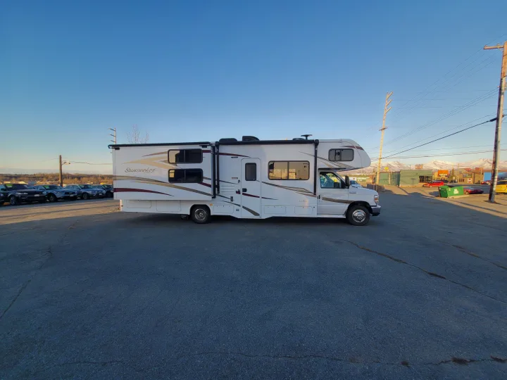 White Sunseeker RV rental, ready for your next adventure. Parked at a lot with distant mountains.. Forest River Sunseeker 2018