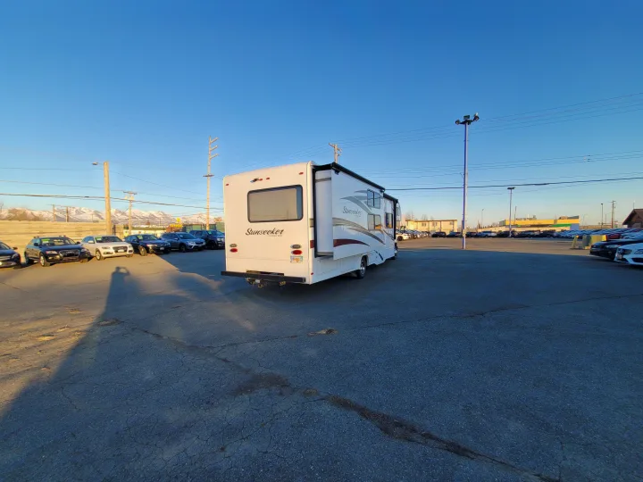 A white Sunseeker motorhome, perfect for RV rental, parked on an outdoor sales lot with other vehicles and snowy mountains.. Forest River Sunseeker 2018