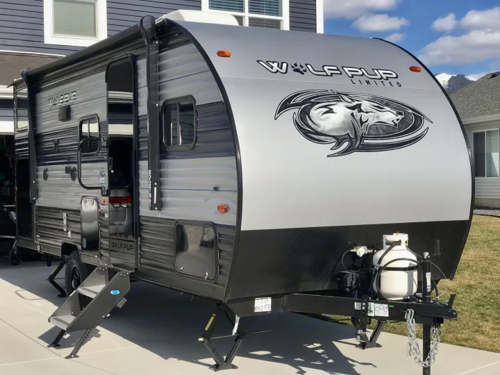 Front view with propane tank, stabilizer steps, storage compartments, etc.. Forest River Wolf Pup 2021