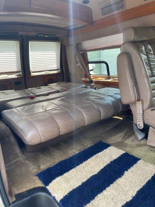 Inside this RV rental, plush leather seats fold into a bed, offering comfort with window blinds and carpeting.. Coachmen Van Conversion 2001