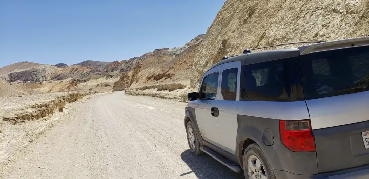 Dusty desert road trip: A silver Honda Element amidst colorful mountains, perfect for off-road adventure or exploring options like an RV rental.. Honda Element 2003