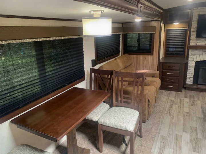 Inside an RV rental: a warm, inviting living space with a dining table, cozy sofa, and fireplace.. Jayco White Hawk 2018