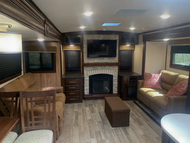 Experience comfort in this RV rental living area: fireplace, TV, sofas, and wood-look floors.. Jayco White Hawk 2018