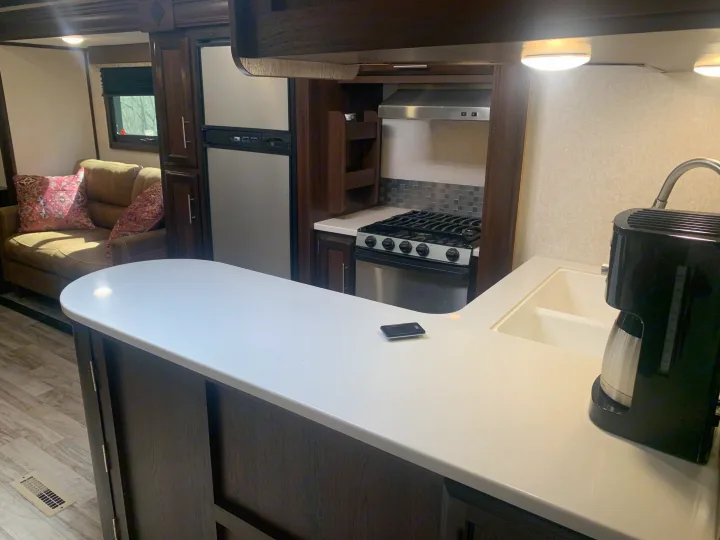 Spacious RV rental interior featuring a modern kitchen with stove, fridge, and ample counter space, plus a cozy living area.. Jayco White Hawk 2018