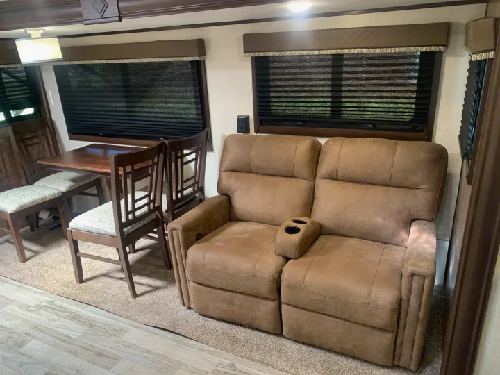 Spacious RV rental interior featuring a dining table, comfortable recliner sofa, and large windows.. Jayco White Hawk 2018