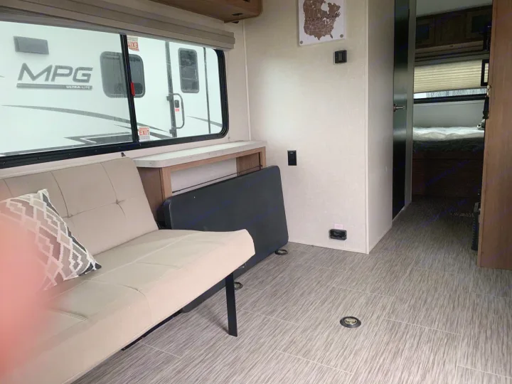 RV rental interior: A versatile space with light-colored sofa, large window, and durable tie-down flooring.. Forest River no boundaries 2020