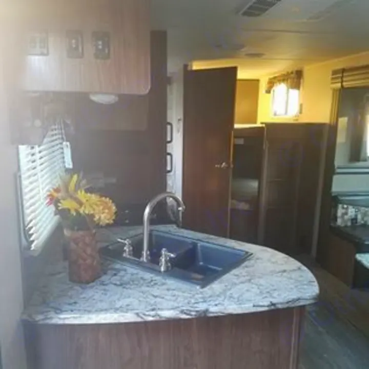 This RV rental features a bright interior kitchen with a double sink, speckled counter, and bunk beds, perfect for your travel adventures.. Heartland Pioneer 2016