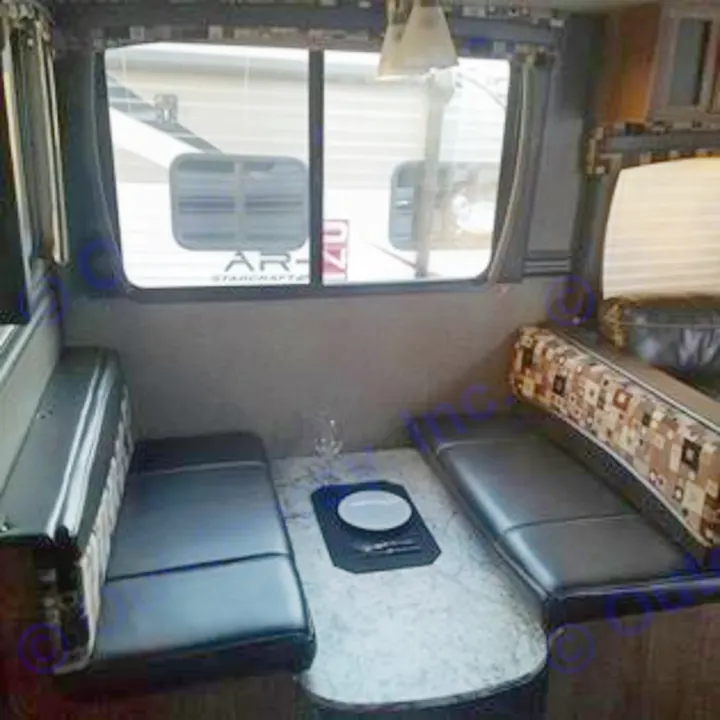 This inviting RV rental dinette offers comfortable black benches & a table, with another RV visible outside. Ready for travel.. Heartland Pioneer 2016