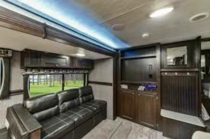 Modern RV rental living area: black sofa, large window views, and built-in entertainment center.. Heartland Pioneer 2016